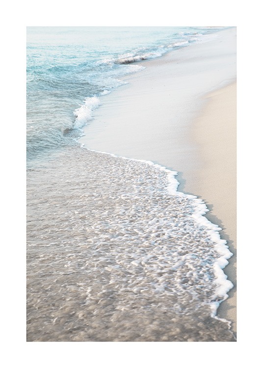  – Fotografi af en strand med lyst sand og bølger, der ruller ind på stranden