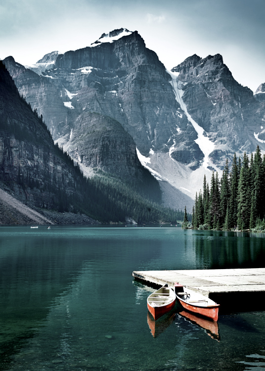 – Fotografi af en sø med en lille badebro og to kanoer foran bjerge