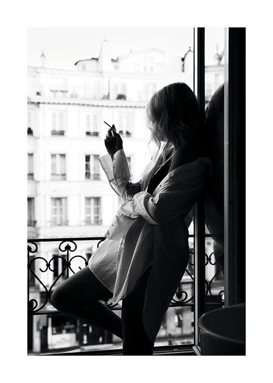  – Sort-hvidt fotografi af en kvinde, der ryger en cigaret i et vindue, iført en stor skjorte