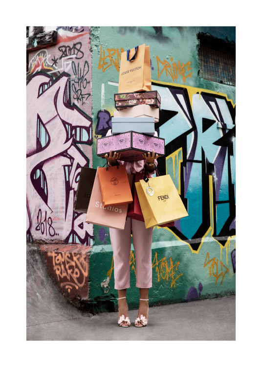  – Fotografi af en kvinde med skoæsker og indkøbsposer i favnen foran en graffitivæg