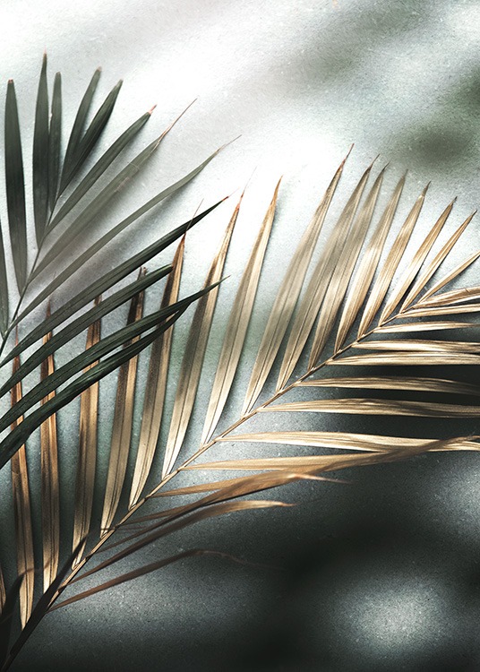  – Fotografi af to palmeblade i guld og grønt på en stenbaggrund