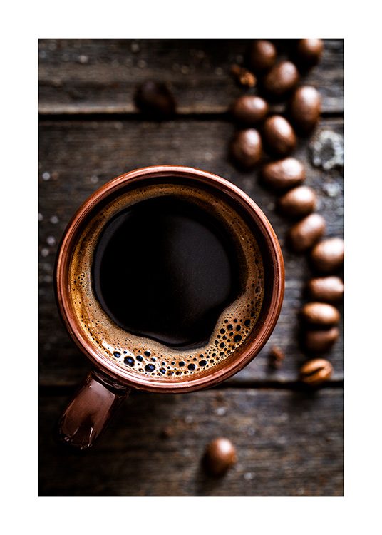  – Fotografi taget ovenfra af en kop kaffe på et træbord med kaffebønner ved siden af