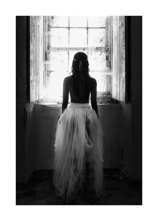 Sort-hvidt fotografi af kvinde, der står foran et vindue iført tylskørt