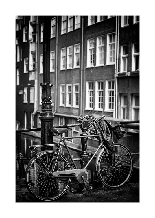  - Sort-hvidt fotografi af en lygtepæl ved siden af en parkeret cykel foran et hus med vinduer