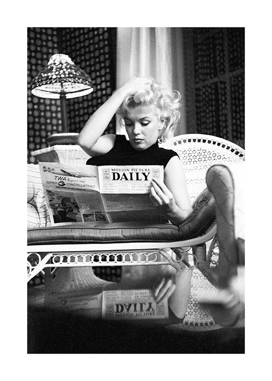  – Sort-hvidt foto af ikonet Marilyn Monroe, der sidder og læser avis på en sofa