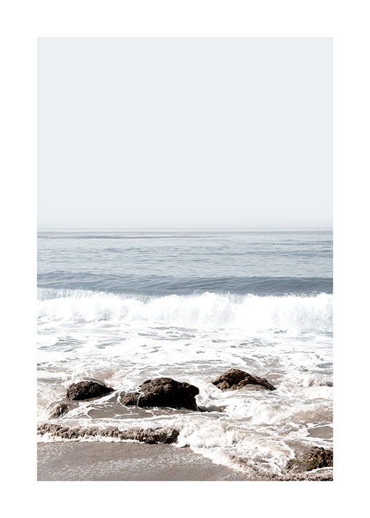  – Fotografi af bølger, der ruller ind på en strand med klipper