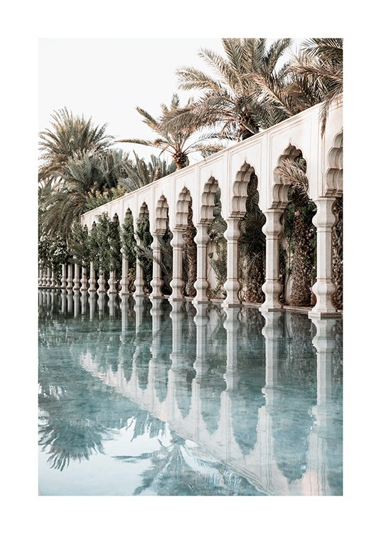  - Fotografi af hvide søjler og udskårne buer ved siden af et bassin med palmer i baggrunden