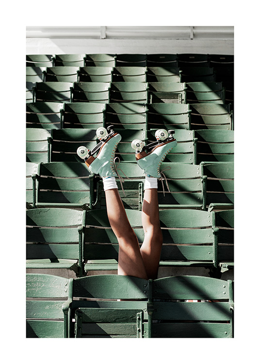  – Fotografi af en person iført rulleskøjter, der stikker benene op mellem grønne sæder på et stadion