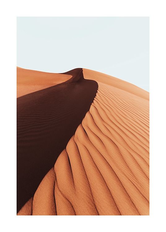  – Fotografi af en sandklit i en ørken med en lyseblå himmel i baggrunden
