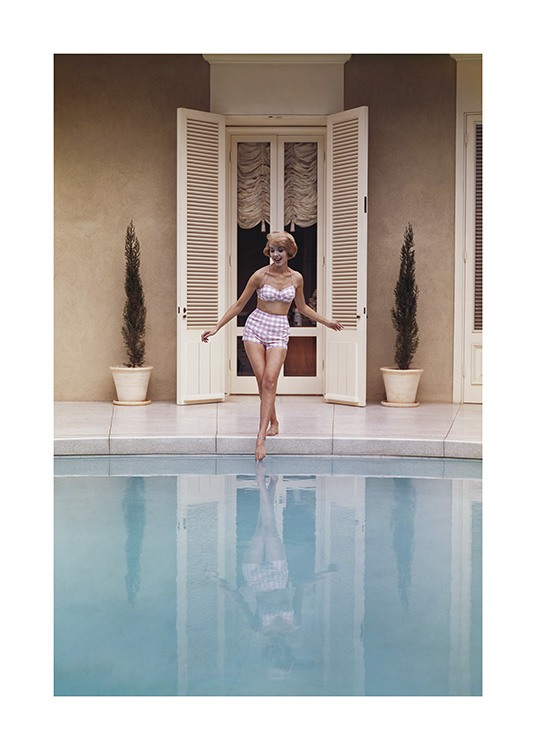  – Fotografi af en kvinde, der stikker foden i en swimmingpool, iført pink og hvid vintage-bikini