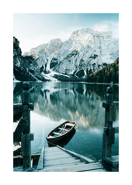  – Fotografi af sneklædte bjerge bag en sø med en båd og trætrappe i forgrunden