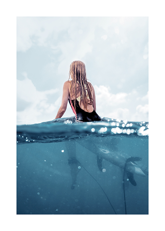  – Fotografi af en kvinde, der sidder på et surfbræt i havet, set bagfra