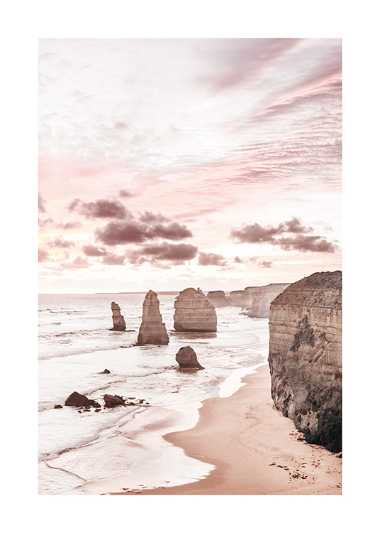  – Fotografi af klipper i og ved havet med en pastelfarvet lyserød himmel bag klipperne