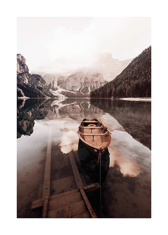  – Fotografi af en stille sø med en lille træbåd og sneklædte bjerge i baggrunden