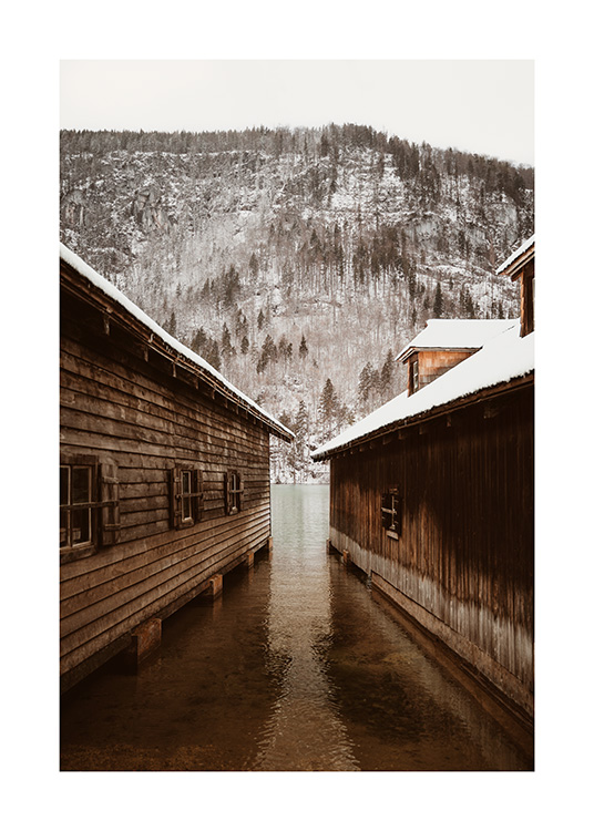 – Fotografi af to bådehuse foran et bjerg med en snedækket skov